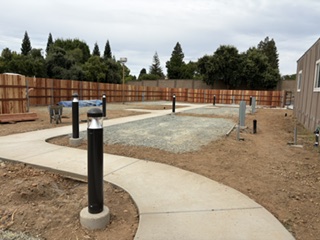 New accessible parking spot and ramp at the Student Village site, with fencing and the building in the background